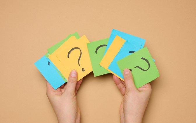 Hands_Holding_Paper_Sheets_With_Question_Marks_original_2274039