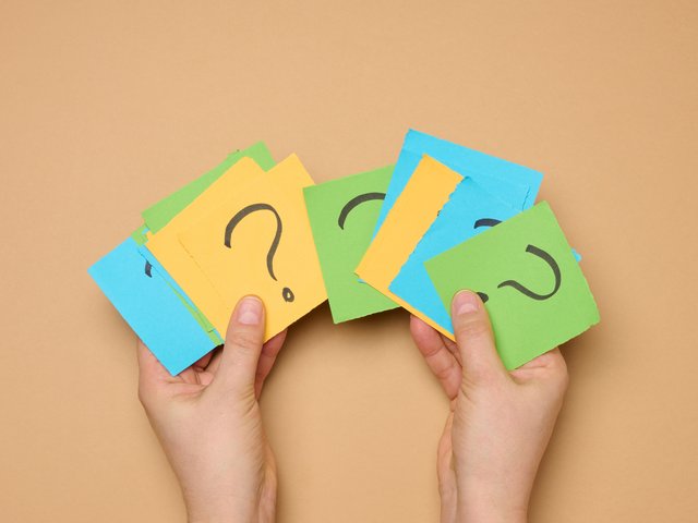 Hands_Holding_Paper_Sheets_With_Question_Marks_original_2274039